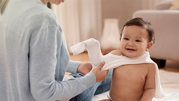 woman putting shirt on baby